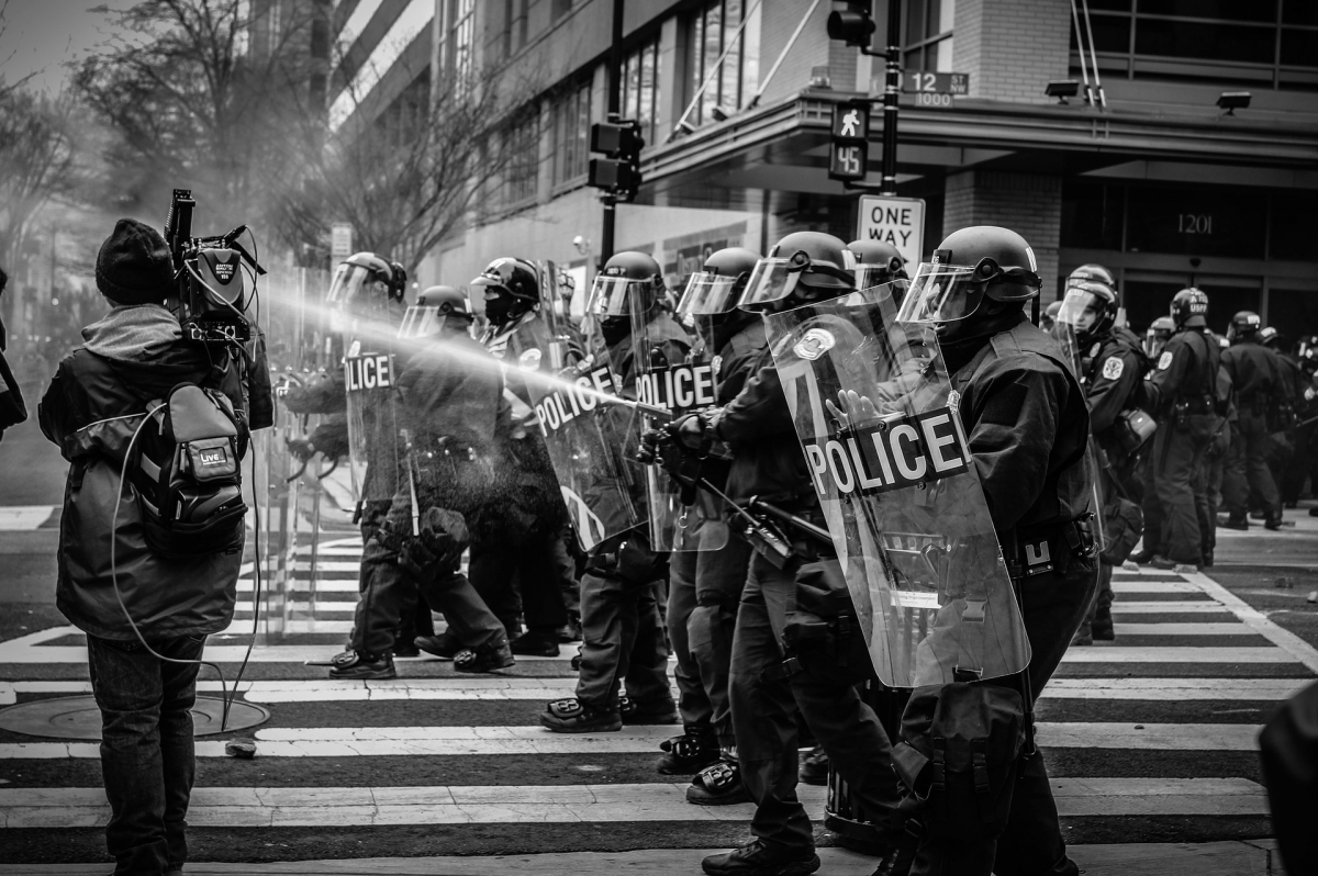 Gewaltsame Eskalationen finden nicht beliebig statt, sondern folgen einer Dynamik, bei der die Outgroup (in den meisten Fällen die Polizei) ihren Anteil an der Konflikteskalation trägt. Bild: StockSnap via pixabay (https://pixabay.com/de/photos/menschen-polizei-protest-wasser-2591693/, CC: https://pixabay.com/de/service/license/)